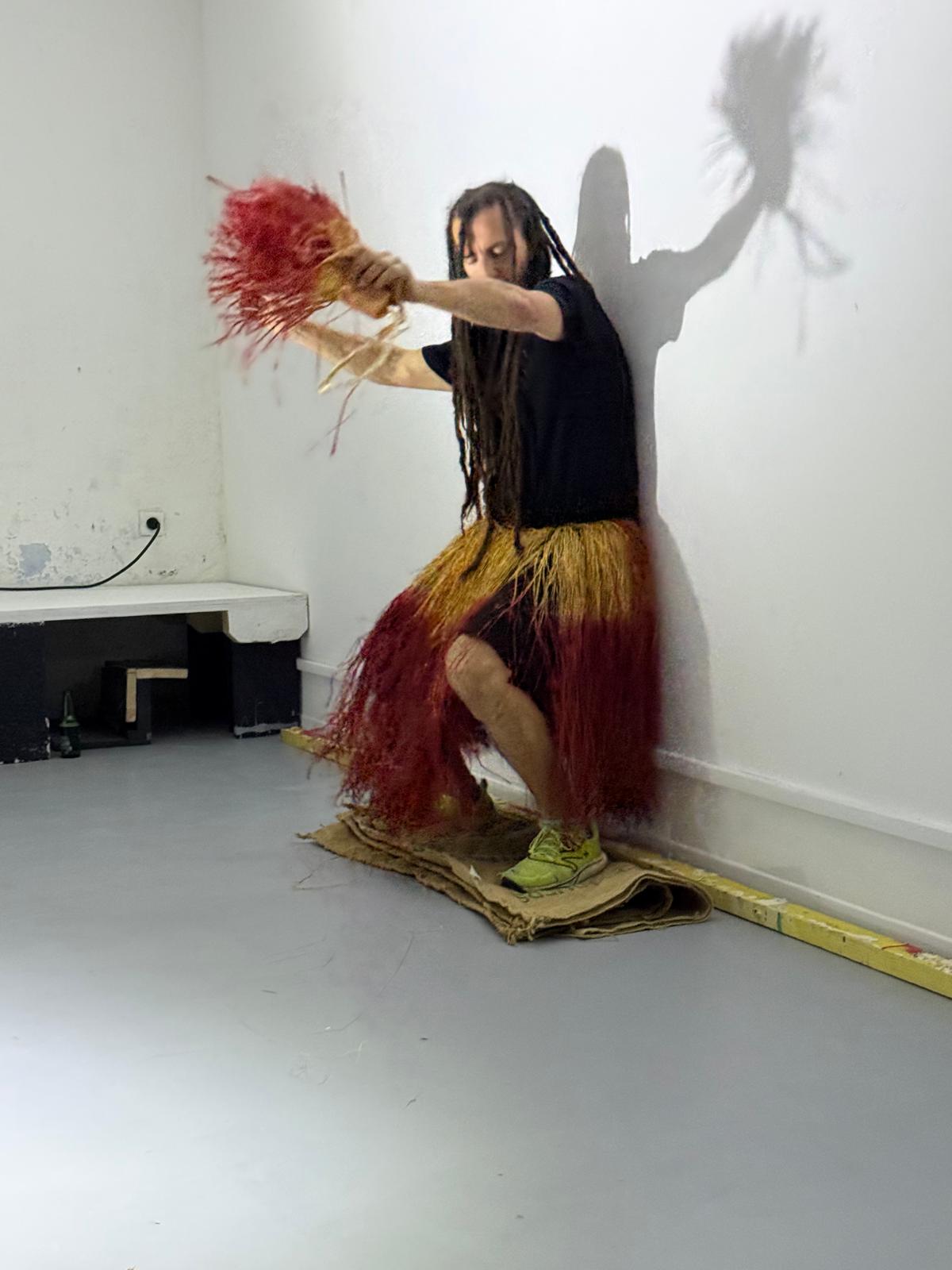 Danseur portant une tenue de raphia rouge et dorée